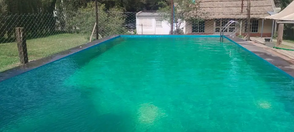 Pileta iluminada con la casa al fondo · La Casona de Bahía