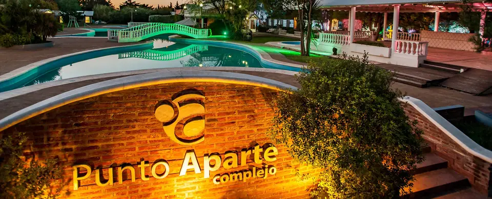 Entrada del complejo con la pileta iluminada · Punto Aparte Multi Espacio