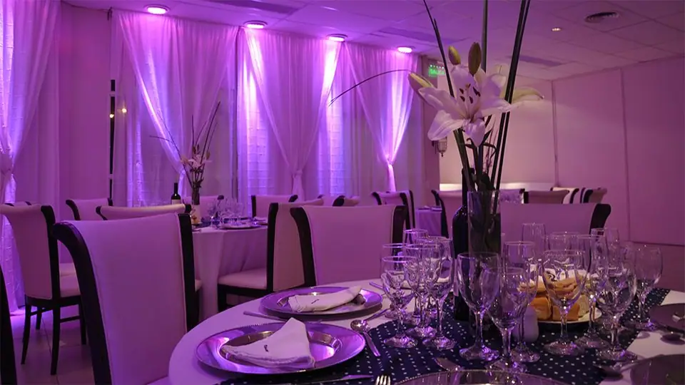 Mesa de banquete con luces violetas · Revoque Eventos